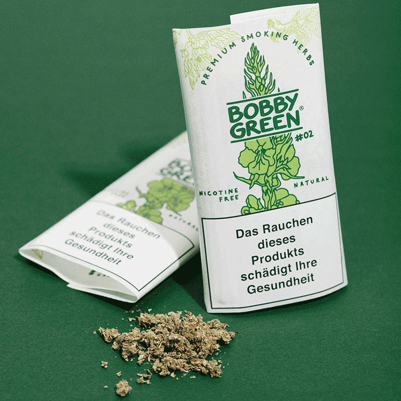 Zwei weiße Verpackungen mit der Aufschrift "Bobby Green #02" und Warnhinweis, grüne Pflanzengrafik, Naturkräuter-Mischung daneben auf grünem Untergrund verstreut.